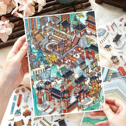 Hand holding an intricate Asian miniature village scene sticker sheet for journaling or scrapbooking