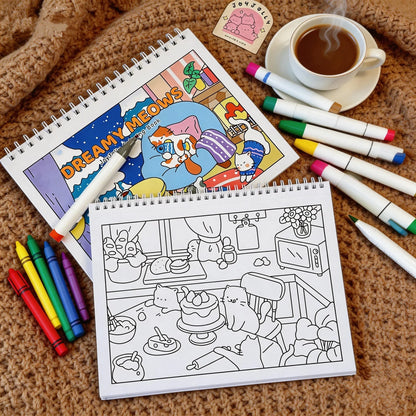 Dreamy Meows cat coloring book with cute cat illustrations, crayons, and markers on a cozy blanket.