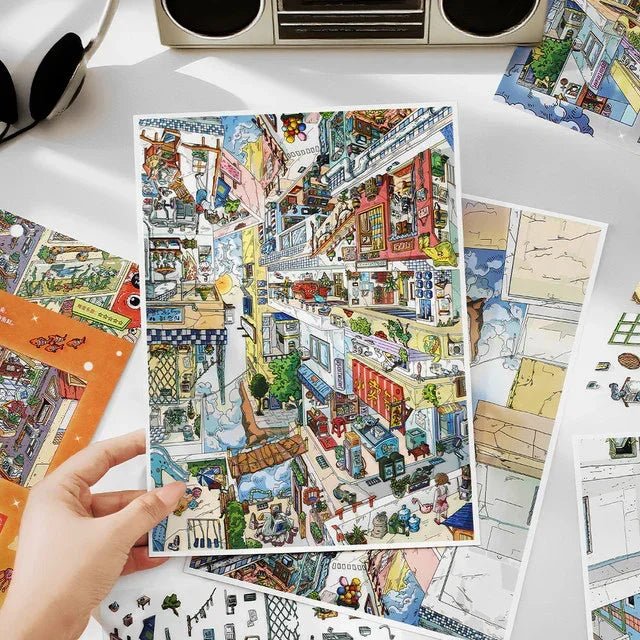 Hand holding illustrated city scene sticker sheet with colorful upside-down houses and streets