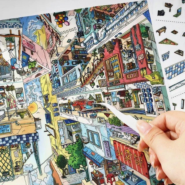 Hand placing sticker on vibrant upside-down miniature city scene, cozy room journaling decor
