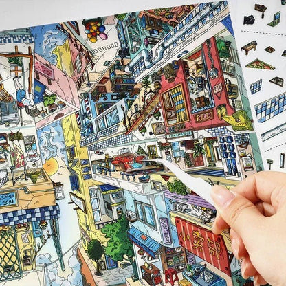 Hand placing sticker on vibrant upside-down miniature city scene, cozy room journaling decor