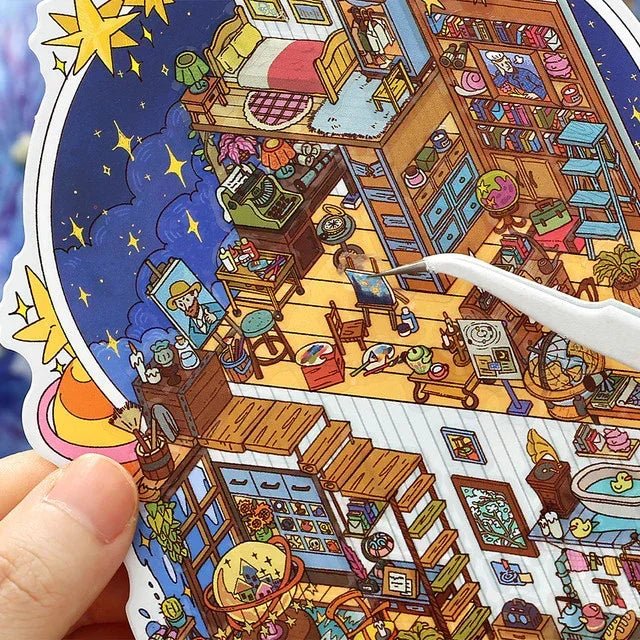 Hand holding colorful miniature room scene sticker with cozy bedroom, art studio, and night sky details