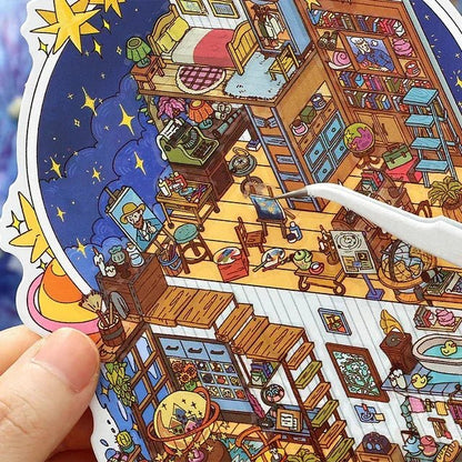 Hand holding colorful miniature room scene sticker with cozy bedroom, art studio, and night sky details