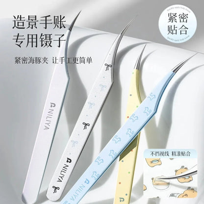 Curved tip tweezers in iridescent blue, white, and yellow with dog and bow designs on a white background.