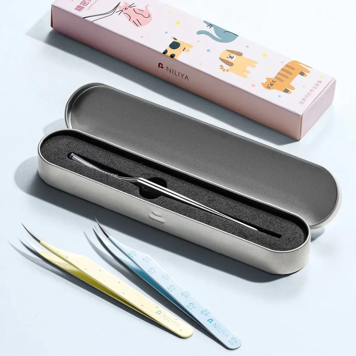 Curved tip tweezers set with iridescent blue, yellow, and silver designs in gift box