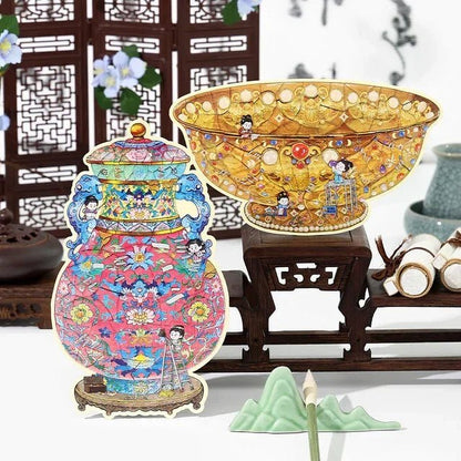 Vintage-style decorative stickers of a golden jade bowl and colorful ruyi vase with cartoon figures, displayed on a wooden stand.