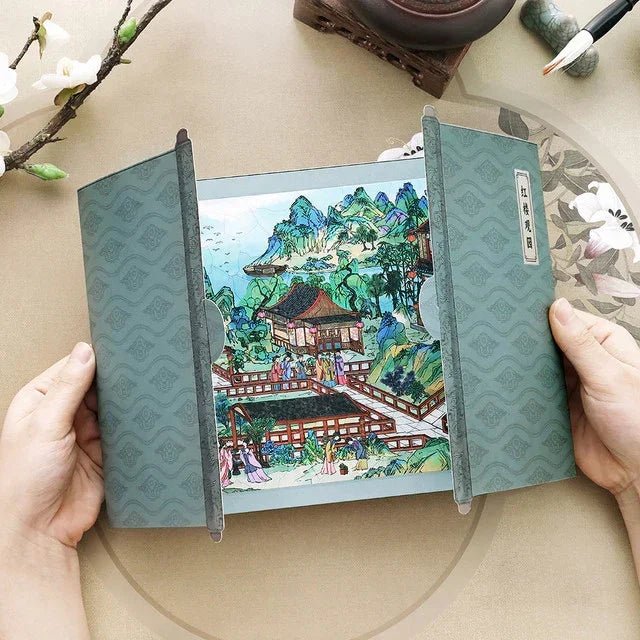 Hand holding vintage style scene sticker with traditional garden, pavilion, and mountains, ideal for journaling or scrapbooking.