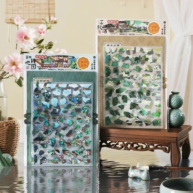 Two sheets of vintage garden scene stickers on a wooden table with floral decor and ceramics.