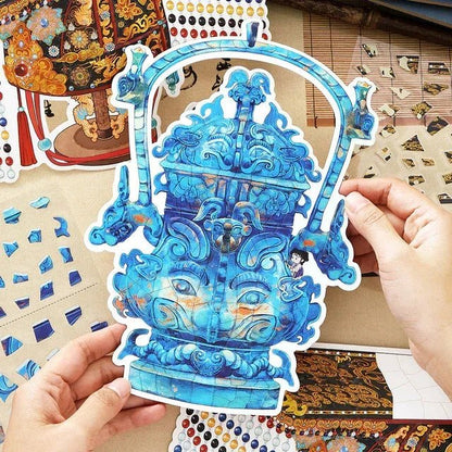 Hands holding large blue vintage urn sticker for journaling or scrapbooking crafts