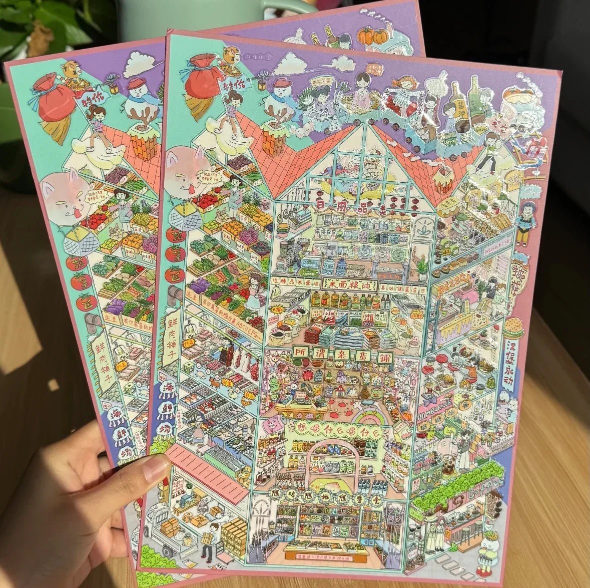 Hand holding colorful illustrated market scene stickers with whimsical characters and food stalls