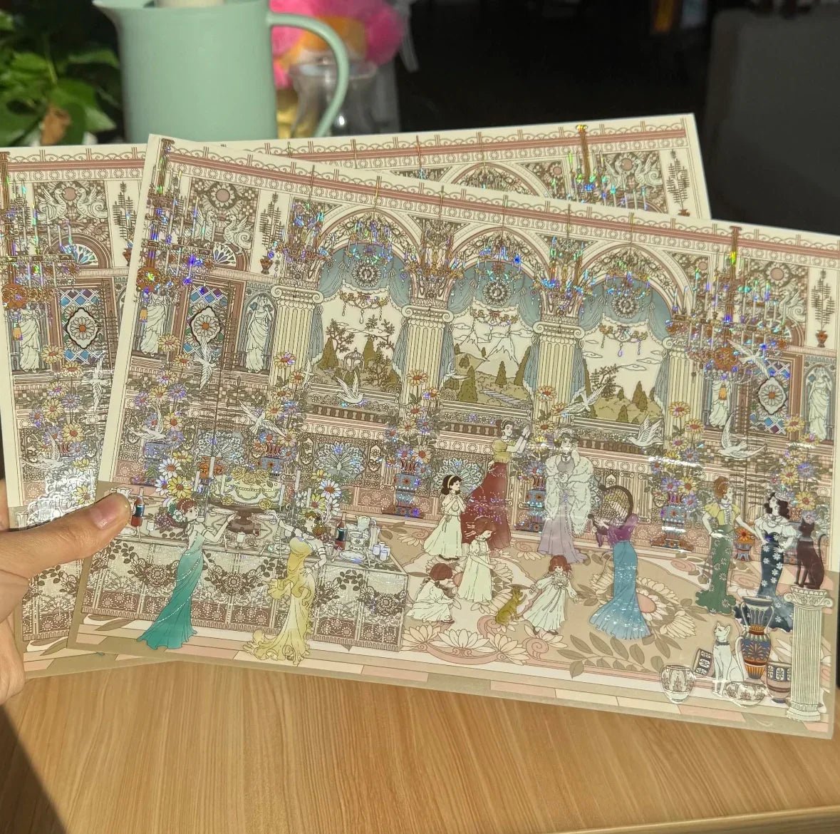 Hand holding ornate scene stickers featuring elegant women in a lavish ballroom setting